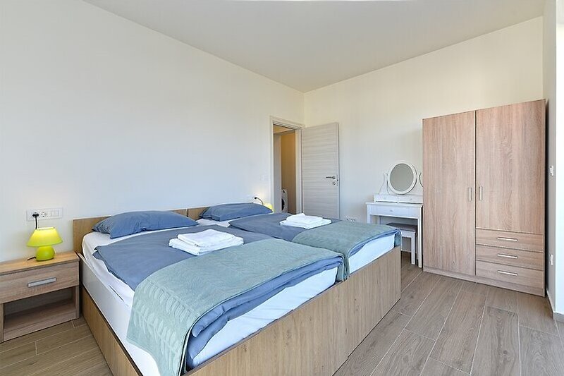 Schlafzimmer mit gemütlichem Bett, Holzmöbeln und elegantem Design.