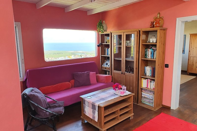 Gemütliches Wohnzimmer mit Holzmöbeln, Kunst an der Wand und bequemer Couch.