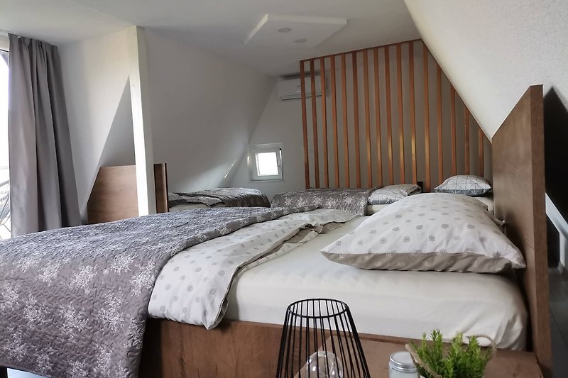 Gemütliches Schlafzimmer mit Holzbett, Tischlampe und Vorhängen. Perfekt für erholsame Ferien.