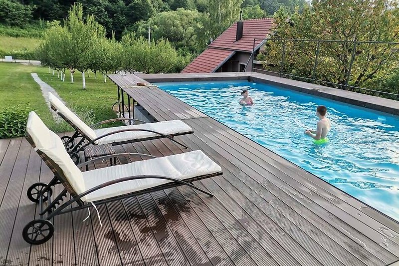 Schwimmbad umgeben von Natur und Outdoor-Möbeln. Perfekt für erholsame Ferien.