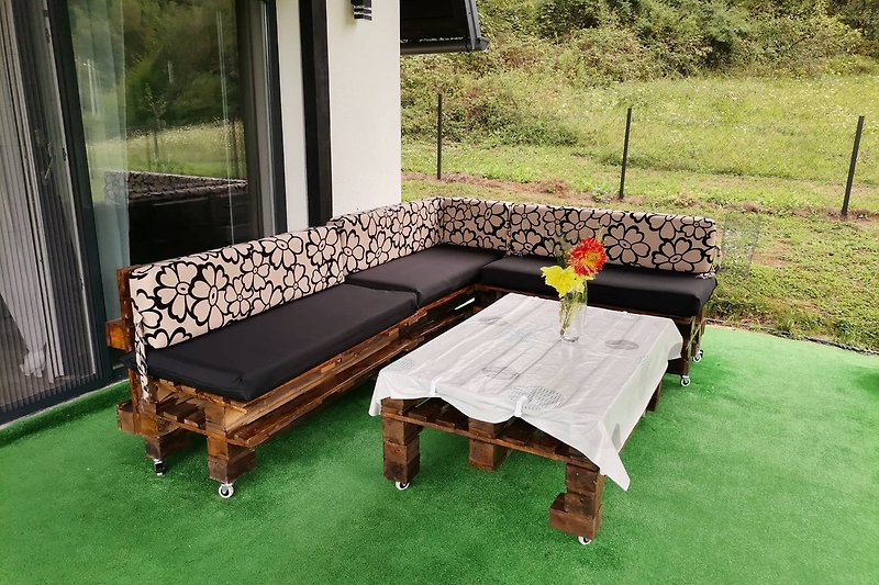 Gemütliche Terrasse mit bequemen Möbeln und Pflanzen. Perfekt für entspannte Ferien im Freien.