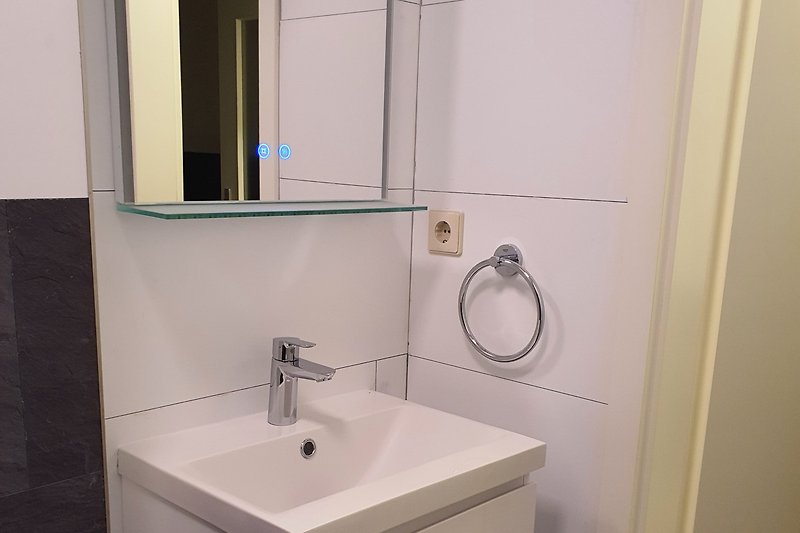 Waschbecken mit wandhängendem Schubladenunterschrank und Spiegel mit Glasablagefläche