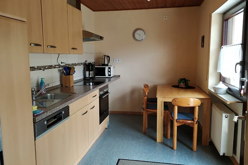 Die Küche mit Spülmachine, Kühlschrank mit Gefrierfach, Mikrowelle, Kaffemaschine, Backofen, und Zugang zur Terrasse.