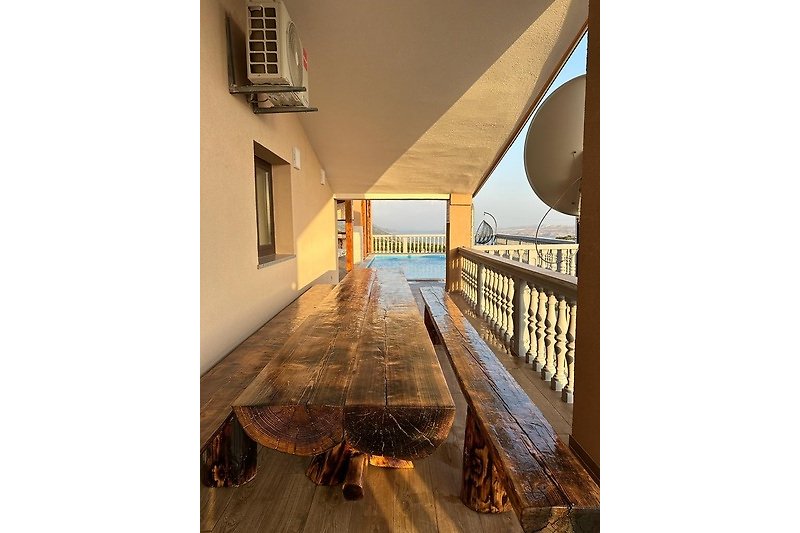 Balkonterrasse mit großem Tisch und Bänken