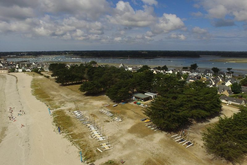 Vue aérienne de la plage et de l'école de voile accessibles en 3 minutes à pied