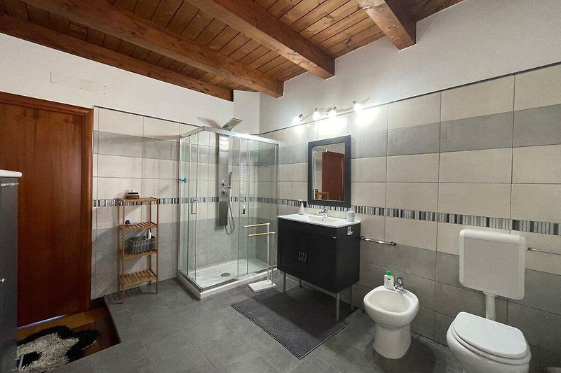 Un bagno moderno con specchio, lavandino e illuminazione. Rilassati e goditi una doccia rinfrescante.
