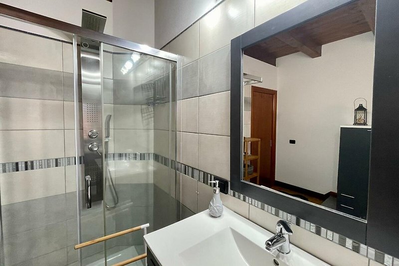 Un bagno moderno con specchio, lavandino e illuminazione. Rilassati e goditi una doccia rinfrescante.