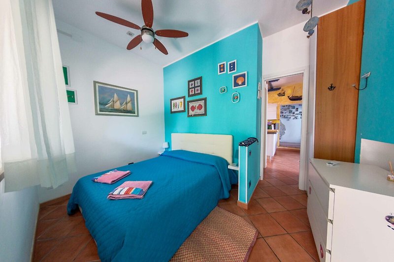 Una confortevole camera da letto con arredamento in legno e ventilatore a soffitto. Rilassati e goditi la tua vacanza!