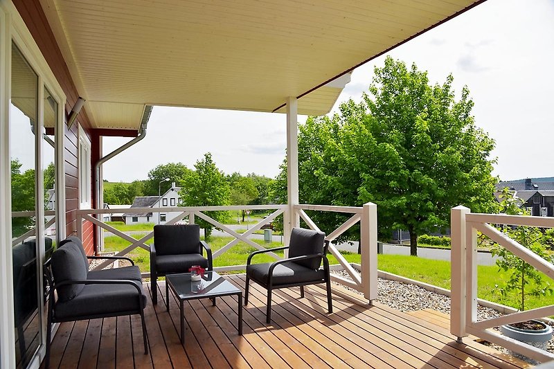 Gemütliche Terrasse mit bequemen Stühlen und grüner Pflanze.
