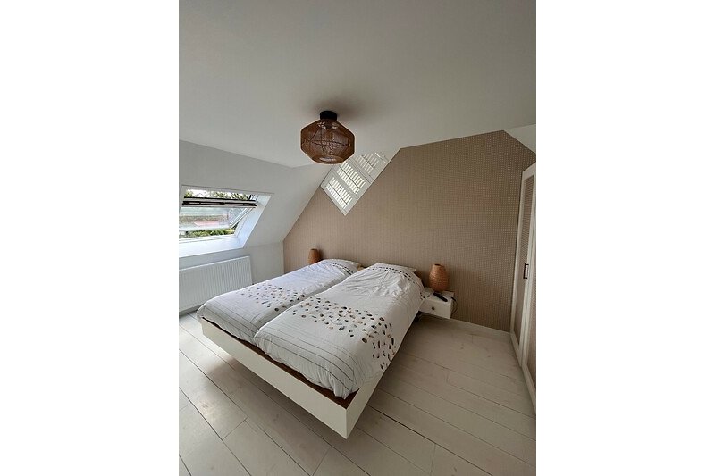Een comfortabel houten bed met zacht beddengoed en een plafond.