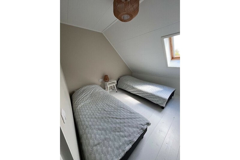 Een comfortabel houten bed met zacht beddengoed en een raam.