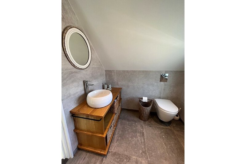 Moderne badkamer met bruine houten vloer, spiegel en toilet.