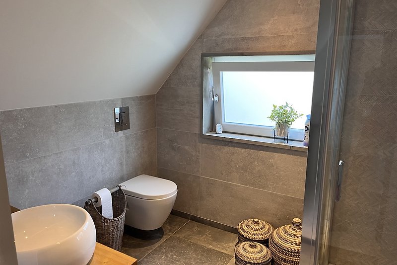 Een moderne badkamer met houten details en een raam.