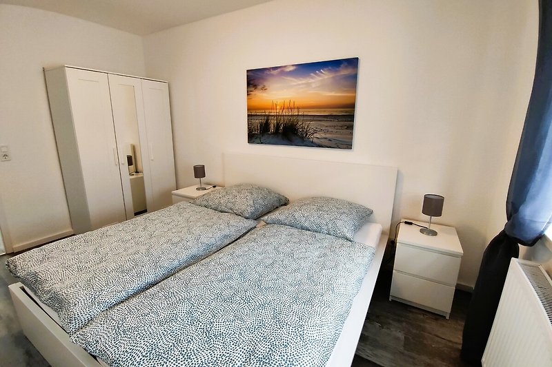Modernes Schlafzimmer mit Holzbettgestell und gemütlicher Bettwäsche.