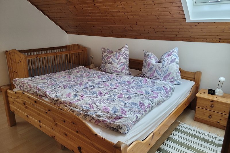 Gemütliches Schlafzimmer mit Holzbett und feststehendem Kinderbett.