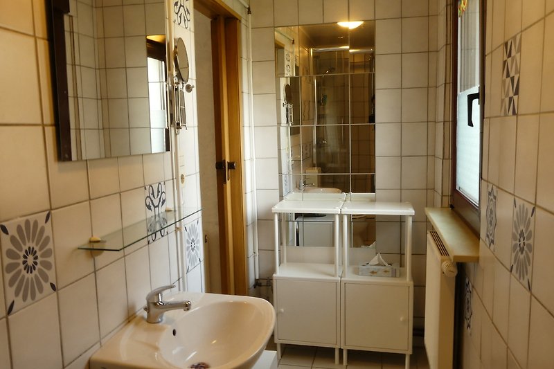 Moderne Badezimmerausstattung mit WC, Dusche, Waschbecken und Fenster.