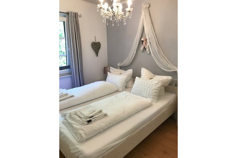 Gemütliches Schlafzimmer mit stilvoller Bettwäsche und Holzmöbeln.