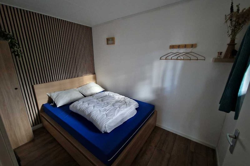 Schlafzimmer mit gemütlichem Bett, Holzmöbeln und Lampe.