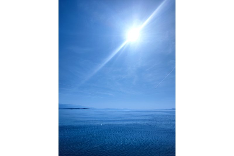 Genießen Sie die ruhige Atmosphäre am See mit dem azurblauen Wasser und dem abendlichen Sonnenuntergang.