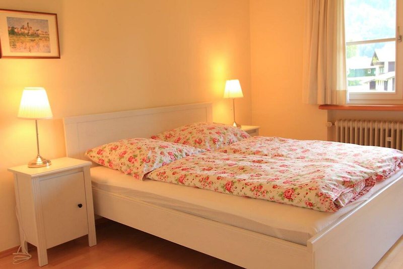 Gemütliches Schlafzimmer mit Holzmöbeln, gelber Beleuchtung und gemütlichem Bett.