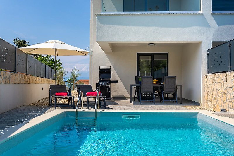 Moderne Villa mit Swimmingpool, Gartengrill, Liegestühlen und einem schattigen Bereich zum Entspannen.