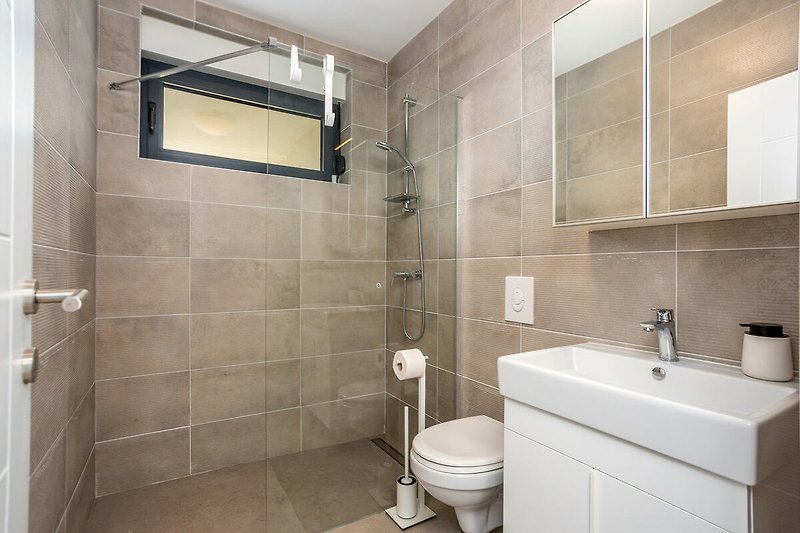 Modern interior of 2 bathrooms upstairs with sinks, walk-in showers, washing machine and sink in the toilet.