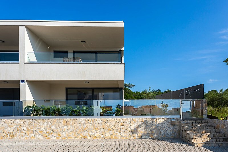 Moderne Villa mit Pool, schattigen Plätzen und mediterranen Pflanzen.