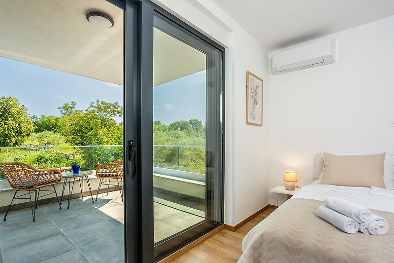 Moderan dizajn interijera s drvenim elementima, udobnim krevetom i velikim prozorom.