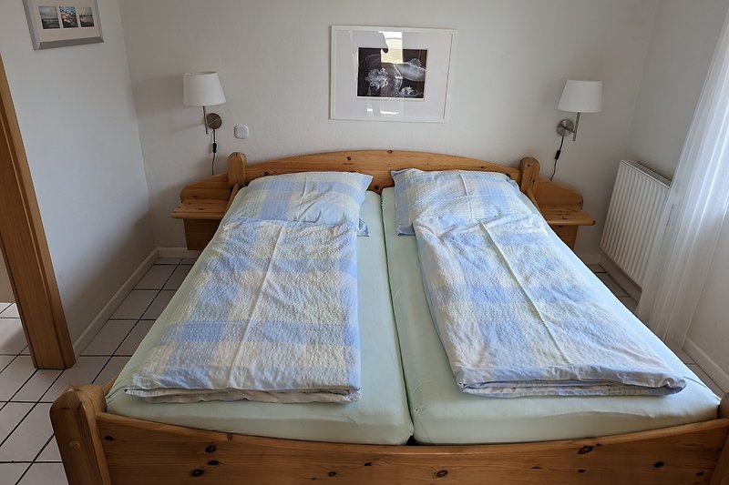 Gemütliches Schlafzimmer mit Holzbett, stilvollem Bilderrahmen und gemütlicher Bettwäsche.