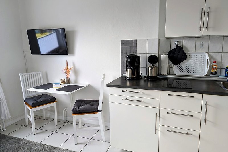 Moderne Küche mit eleganten Schränken, Küchengeräten und Holzakzenten.