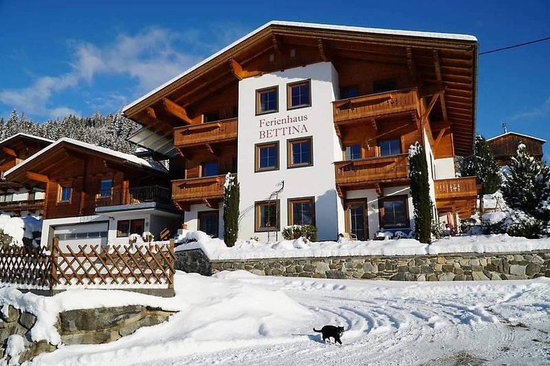 Gemütliches Holzhaus mit verschneitem Bergpanorama und winterlicher Atmosphäre.