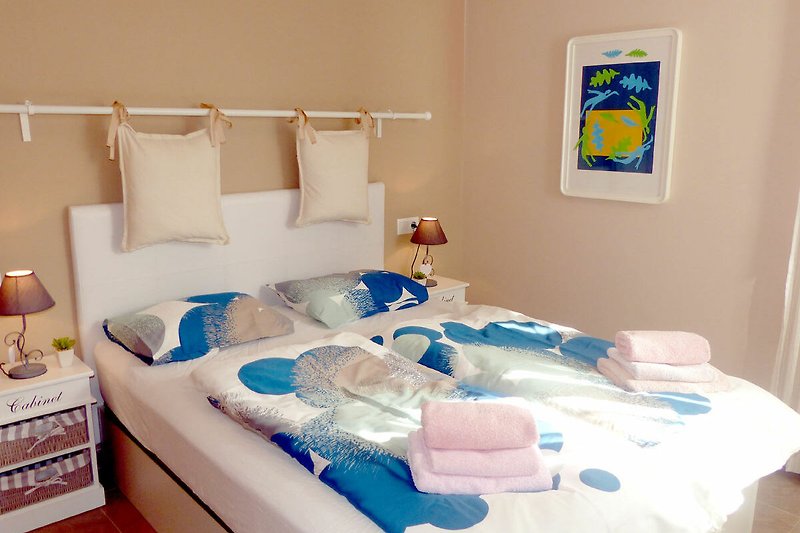 Comfortabele slaapkamer met een blauw bed en houten meubels.