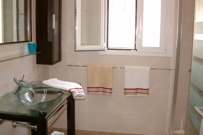 Mooi ingerichte badkamer met houten vloer, raam en wastafel.