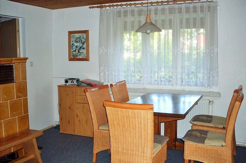 Gemütliches Wohnzimmer mit Holzmöbeln und großen Fenstern und Ofen