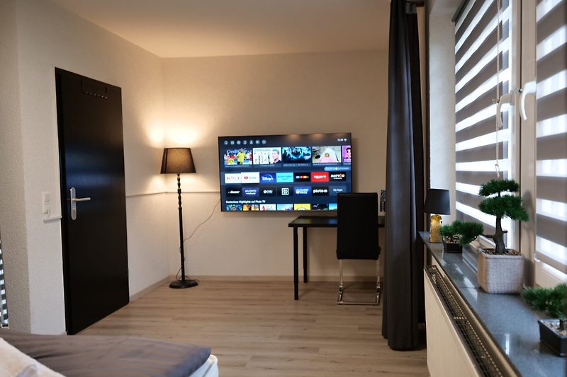 Stilvolles Wohnzimmer mit Holzmöbeln, Fernseher und Pflanzen.