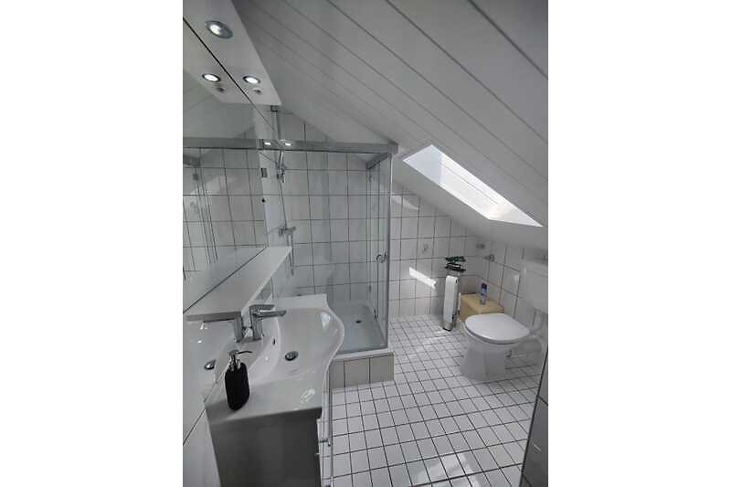 Stilvolles Badezimmer mit modernem Waschbecken, Spiegel und Glasdetails.