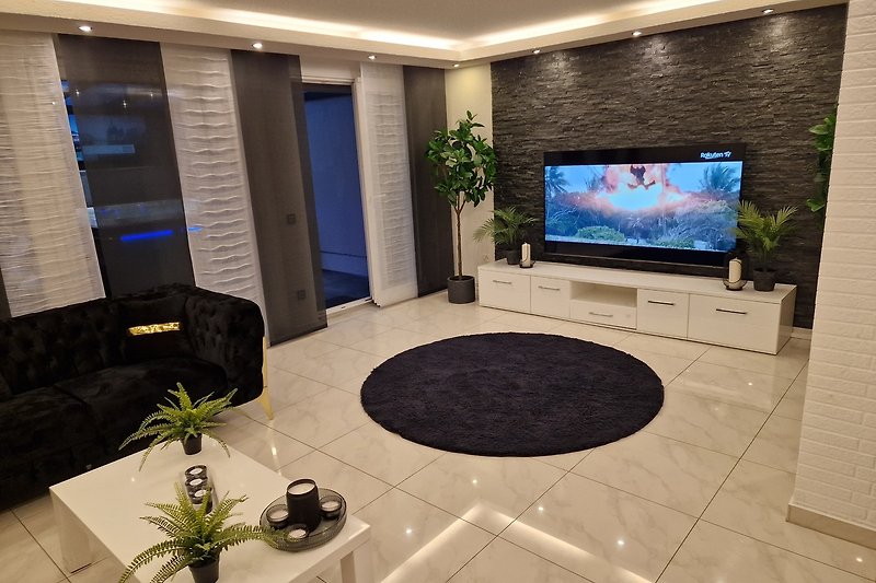 Stilvolles Wohnzimmer mit Pflanzen, moderner Einrichtung und Fernseher.