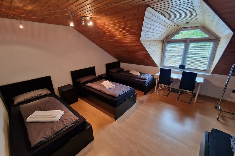 Gemütliches Wohnzimmer mit bequemer Couch, Holzmöbeln und Fensterblick.