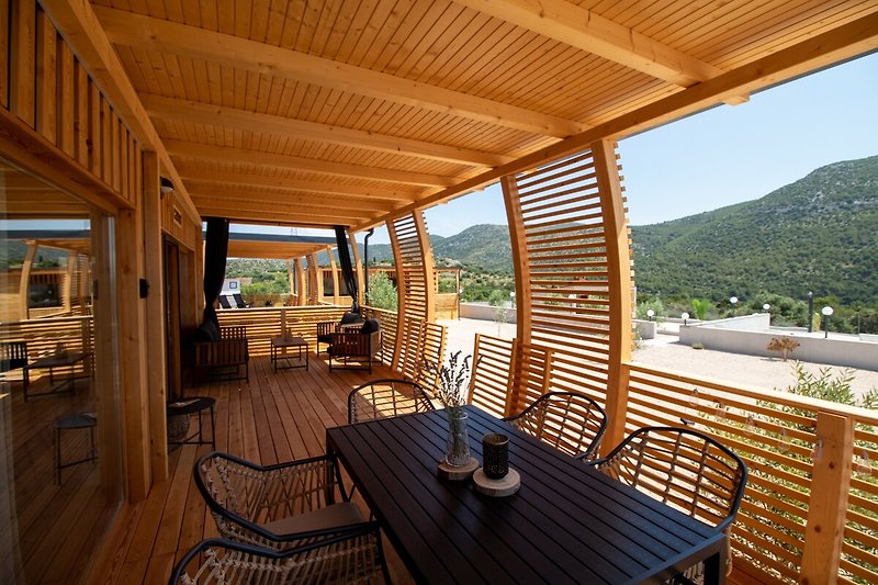 Schönes Ferienhaus mit Holzterrasse und Blick auf die Landschaft.