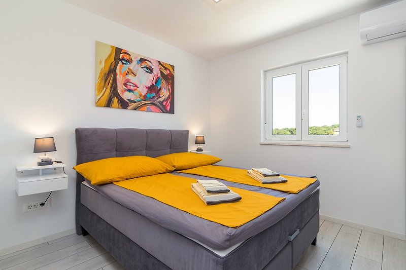 Udobna spavaća soba s drvenim krevetom i narančastim detaljima.
