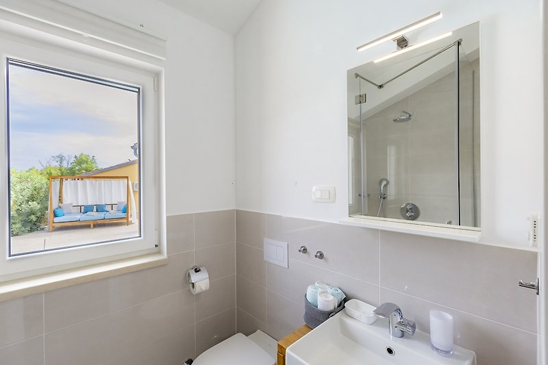 Udobna kupaonica s bijelim umivaonikom i ogledalom