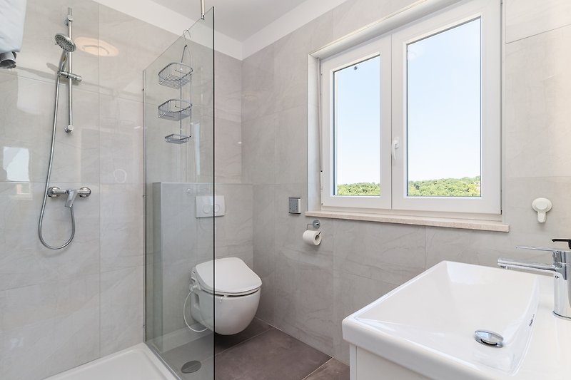 Moderan kupaonski prostor s bijelim umivaonikom i tušem.