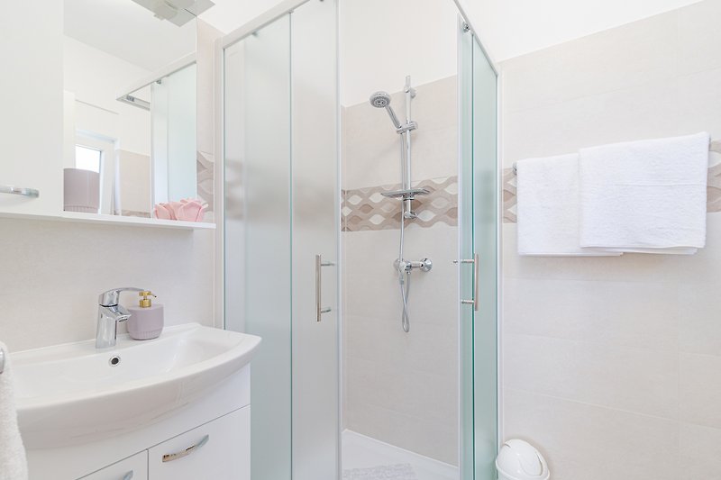 Luksuzna kupaonica s modernim slavinama, tušem i ogledalom.