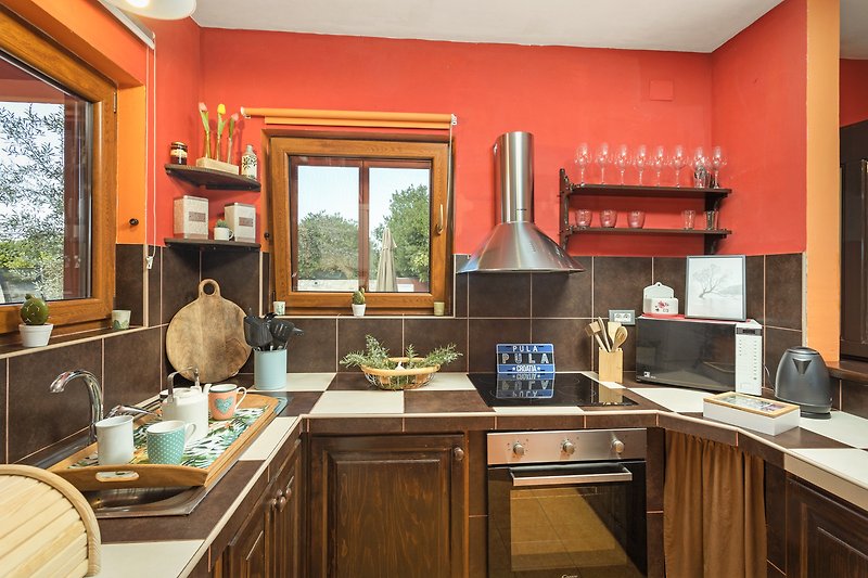 Pogled na kuhinju s drvenim elementima i prozorom. Idealno mjesto za kuhanje i opuštanje.