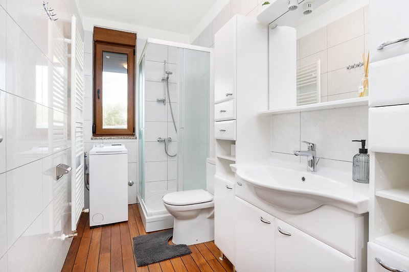Prekrasna kupaonica s ljubičastim detaljima i drvenim ormarićem.