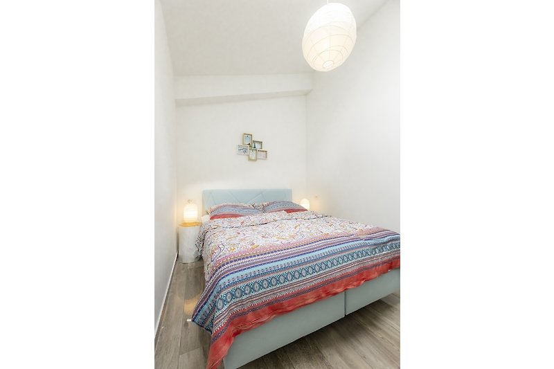 Udobna spavaća soba s drvenim krevetom i udobnim namještajem.