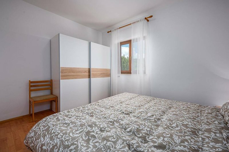 Predivna spavaća soba s udobnim krevetom i drvenim namještajem.