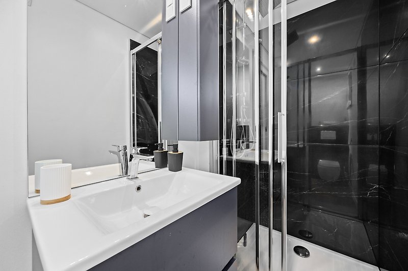 Elegantna kupaonica s modernim namještajem i staklenim tušem.
