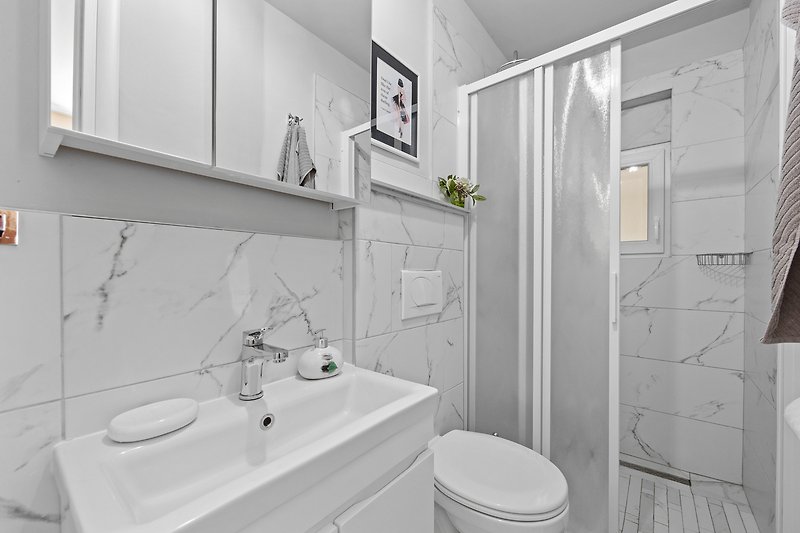 Predivna kupaonica s ljubičastim zidom, keramičkim umivaonikom i modernim slavinama.