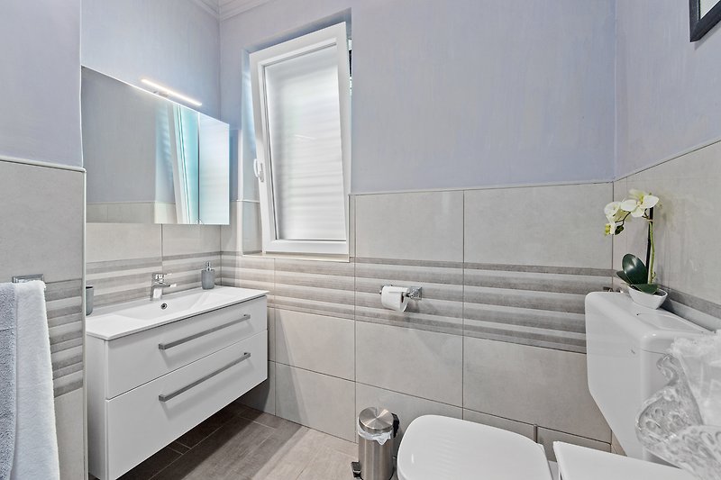 Predivna kupaonica s ljubičastim umivaonikom i modernim slavinama.